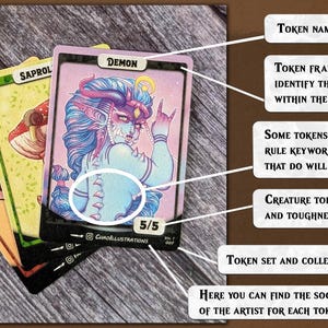 May include: A collection of fantasy game cards with creature illustrations. The central card shows a blue-skinned demon with horns, labelled "DEMON" with a power/toughness of 5/5. Other cards feature a mushroom and a dinosaur. The cards are on a wooden surface.