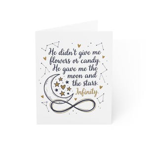 May include: A white greeting card with a navy blue and gold design. The card features the text "He didn't give me flowers or candy. He gave me the moon and the stars. Infinity." with illustrations of a crescent moon, stars, and an infinity symbol.