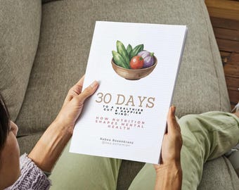 Op de afbeelding: Een persoon houdt een boek met de titel "30 Days" vast. De omslag toont een aquarel illustratie van groenten in een houten kom. De tekst luidt: "Voor een gezondere darm en een gelukkiger geest: Hoe voeding de mentale gezondheid vormgeeft."