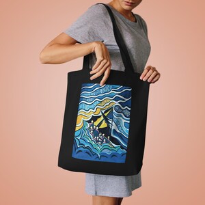 May include: Black tote bag featuring a blue and yellow illustration of a ship on the water. The text "Then he arose and rebuked the wind and said to the sea, "Peace, be still!" and the wind ceased, and there was a great calm." is printed on the bag.
