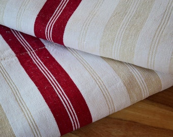 May include: Two pieces of striped fabric folded on top of each other. The fabric is white with thin beige stripes and thick red stripes.