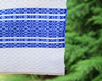 May include: White fabric with blue embroidered stripes and a geometric pattern. The fabric has a textured surface.