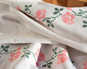 May include: White linen tablecloth with a green and pink floral embroidery design. The tablecloth is folded in half and the embroidery is visible on both sides.