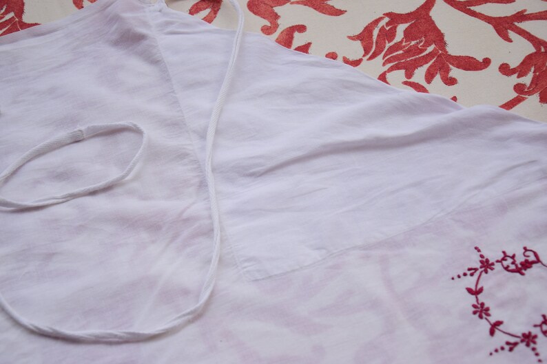 May include: White cotton fabric with a white drawstring and red embroidered floral design.