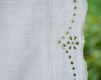 May include: White linen tablecloth with a scalloped edge and a delicate eyelet design. The tablecloth has a subtle texture and a simple, elegant look.