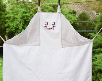 May include: A white linen apron with red embroidered floral details and the letters "JJ" in the center.