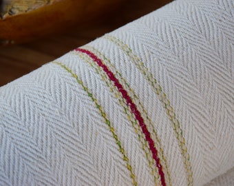 May include: A white fabric roll with a herringbone pattern and red and green stripes.
