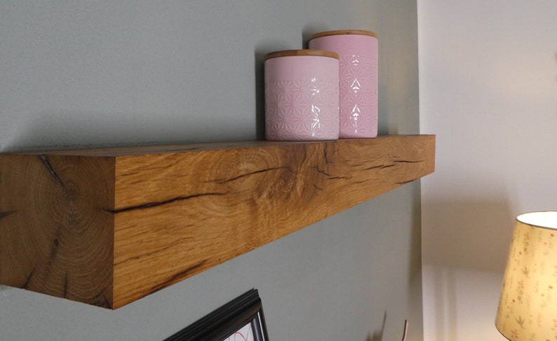 Puede incluir: Una estanter&iacute;a de madera r&uacute;stica con un acabado de madera natural, montada en una pared gris. Dos tarros de cer&aacute;mica rosa con un patr&oacute;n floral se muestran en la estanter&iacute;a.