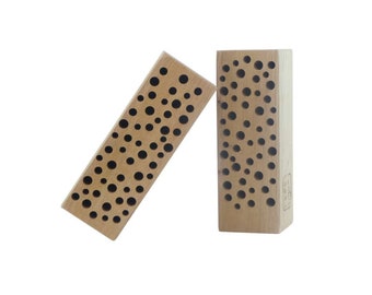 Puede incluir: Dos bloques de madera con un patrón de agujeros redondos. Los bloques son de color marrón claro y tienen un acabado de madera natural.