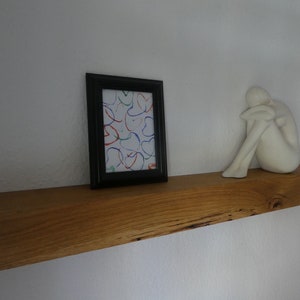 Puede incluir: Una estanter&iacute;a de madera con una escultura de cer&aacute;mica blanca y un cuadro enmarcado con arte abstracto de colores. La estanter&iacute;a est&aacute; hecha de madera natural con un acabado r&uacute;stico.