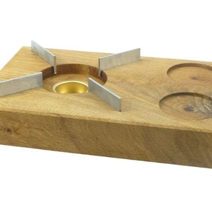 Op de afbeelding: Een houten fonduebrander met een messingkleurig midden en vier metalen steunen. Aan de rechterkant bevinden zich twee cirkelvormige inkepingen. Het hout heeft een natuurlijke nerf en een warme, bruine kleur.