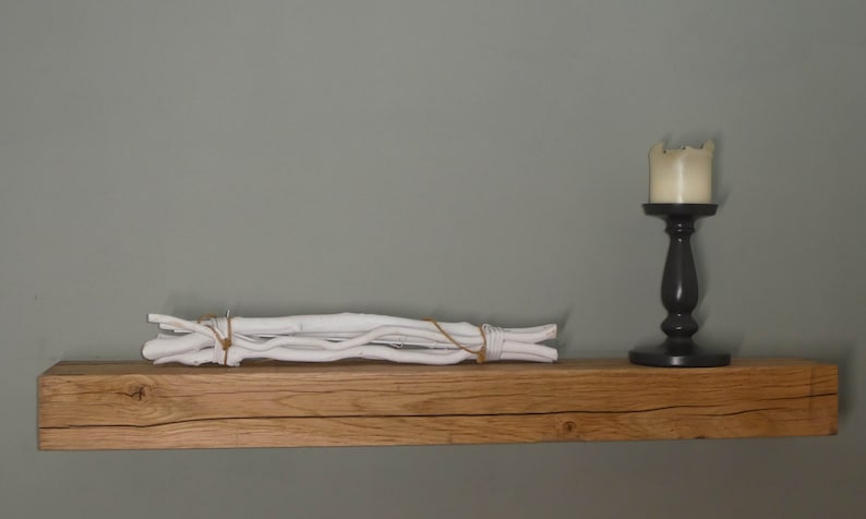 Puede incluir: Una estanter&iacute;a de madera r&uacute;stica con una decoraci&oacute;n de ramas blancas y un candelero negro con una vela blanca en la parte superior.