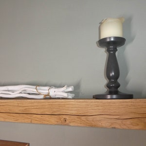 Puede incluir: Una estanter&iacute;a de madera r&uacute;stica con un candelero blanco y un manojo de madera flotante blanca en la parte superior. La estanter&iacute;a est&aacute; hecha de madera natural con un nudo y un patr&oacute;n de veta.