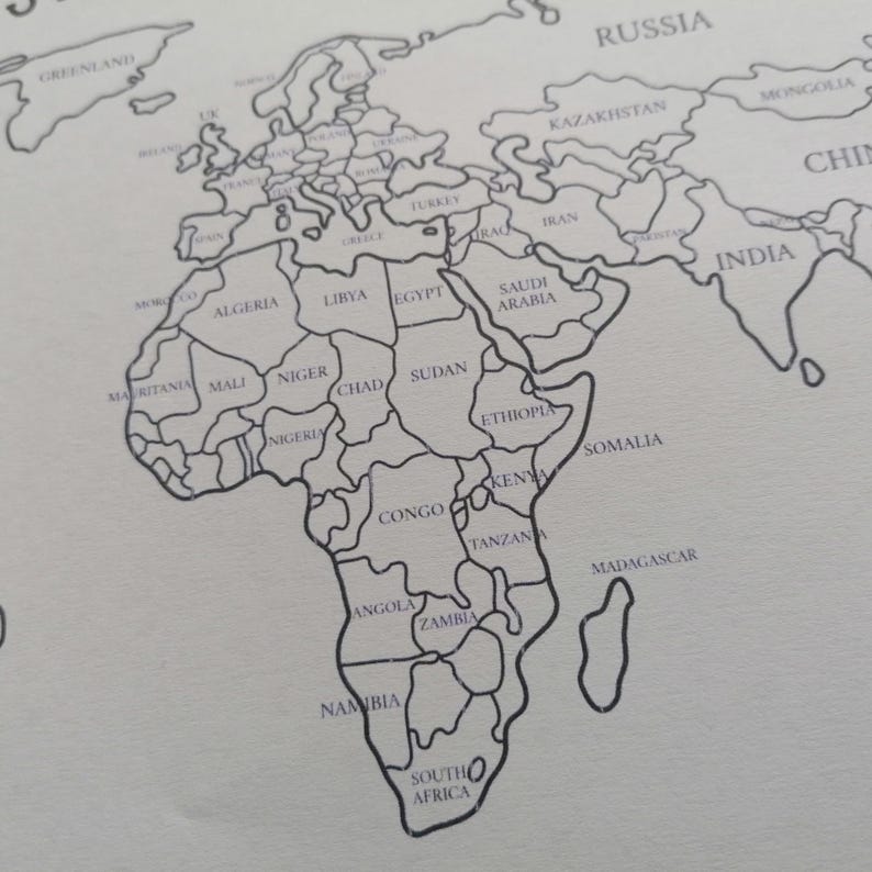 May include: A black and white line drawing of a world map printed on a light surface. The map features clearly outlined country borders and labels for various nations including Algeria, Libya, Egypt, Sudan, Ethiopia, Somalia, and South Africa.