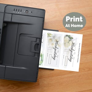 May include: A black printer is shown printing a German wedding cheque template. The template features floral designs and the word "Hochzeitstag". The image includes the text "Print At Home".