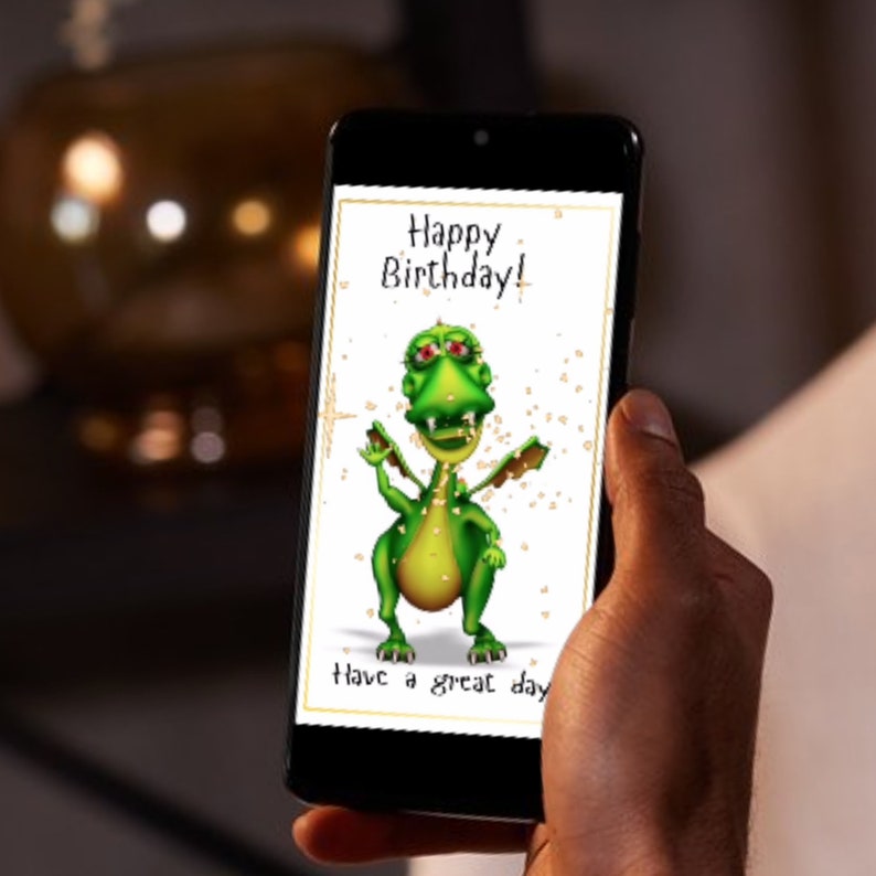 A smartphone displaying a birthday card with a green cartoon dragon and the text 'Happy Birthday! Have a great day'.