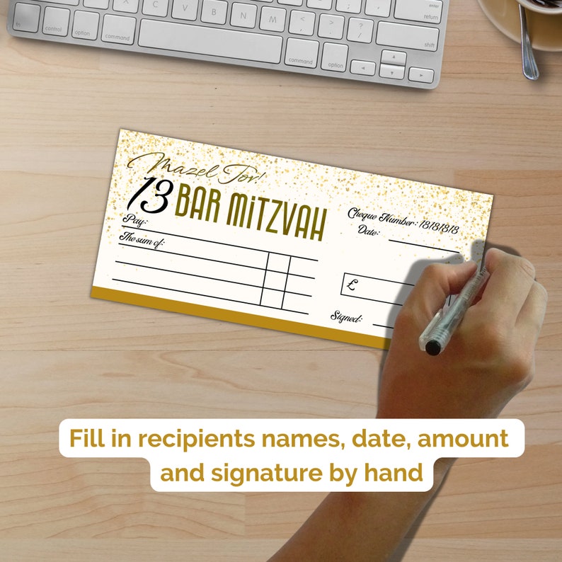 May include: A rectangular novelty check with a white background, gold glitter accents, and black text reading Mazel Tov! 13 Bar Mitzvah. The check includes fields for Pay, The sum of, Cheque Number 18181818, Date, a pound symbol, and Signed.