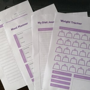 May include: A set of printable planner pages with a purple and white color scheme. The pages include a grocery list, meal planner, diet journal, and weight tracker. The weight tracker has a 30-day weight tracker section with 30 weight icons.