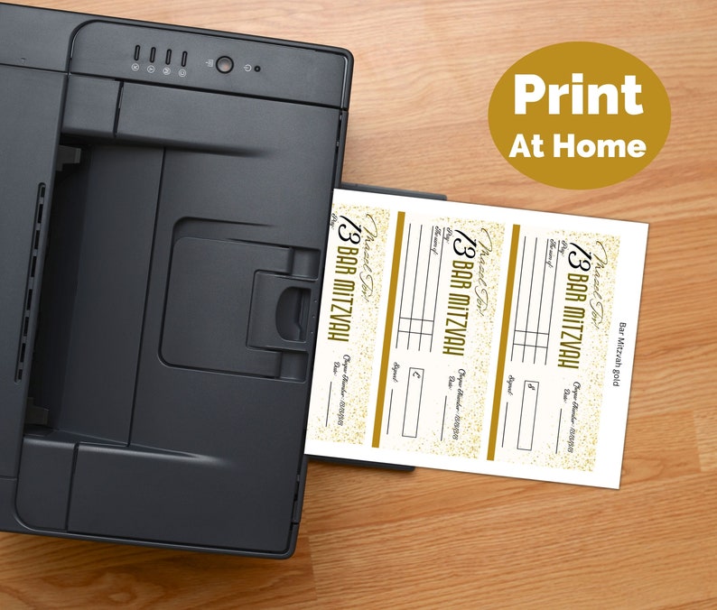 May include: A black printer feeding a sheet of paper with three printed Bar Mitzvah check templates. Each template features gold glitter accents, the text "Mazel Tov!", "BAR MITZVAH", "Pay", "Date", "Check Number", and "Signature". A gold circle with "Print At Home" is visible.