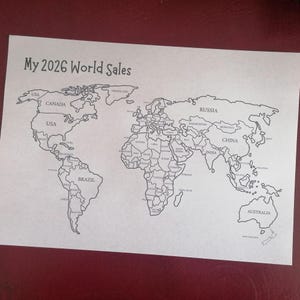 May include: A white paper sheet featuring a black line-art world map with the text My 2026 World Sales printed at the top. The map includes labeled countries such as USA, Canada, Brazil, Russia, China, and Australia, with clear borders.