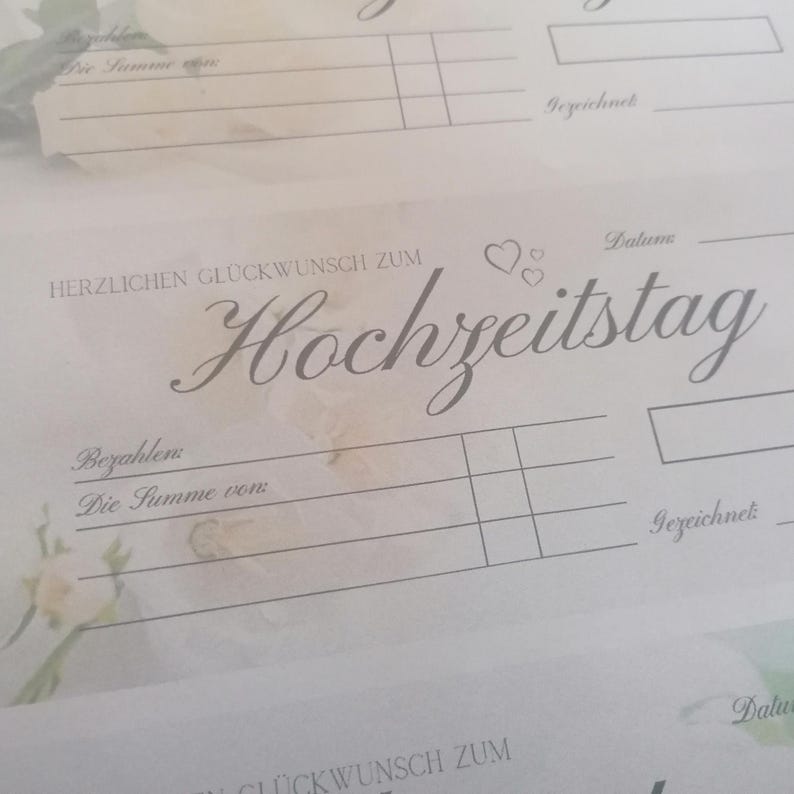 May include: Close-up of a light-colored paper with the German phrase "HERZLICHEN GL&Uuml;CKWUNSCH ZUM Hochzeitstag" in elegant script. The paper has lines for filling in details and the word "Datum" is visible. Soft floral accents are in the background.