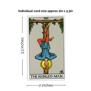 May include: The Hanged Man tarot card, a traditional design with a man hanging upside down from a tree branch. The card is 2 inches wide and 3.3 inches tall.