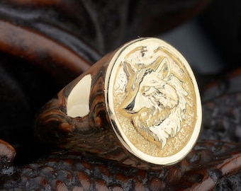 May include: A gold ring with a wolf head design. The ring is oval shaped and the wolf head is in high relief.