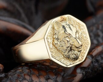 May include: A gold ring with a detailed wolf head design on the face of the ring. The ring is octagonal in shape.