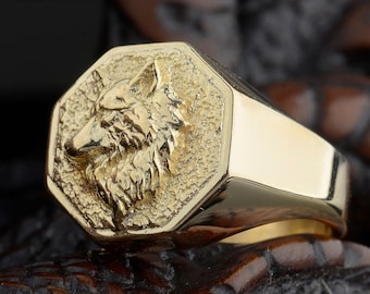 May include: A gold signet ring with a detailed wolf head design. The ring is octagonal in shape and has a smooth, polished finish.