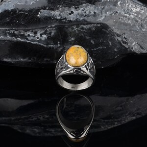 Peut inclure: Une bague en argent avec une pierre ovale jaune et blanche sertie dans un motif d&eacute;taill&eacute;.