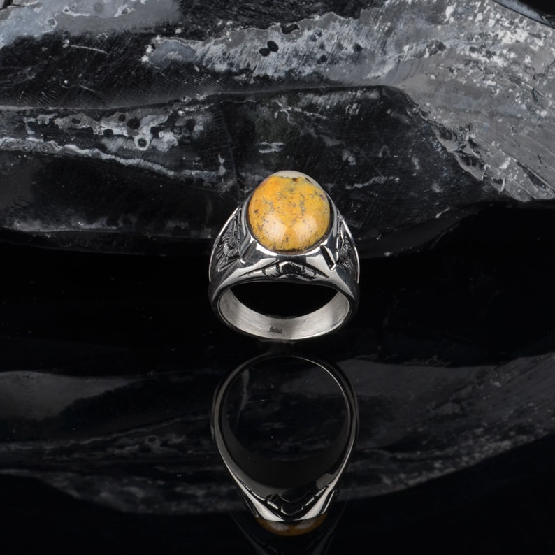 Peut inclure: Une bague en argent avec une pierre ovale jaune et blanche sertie dans un motif d&eacute;taill&eacute;.