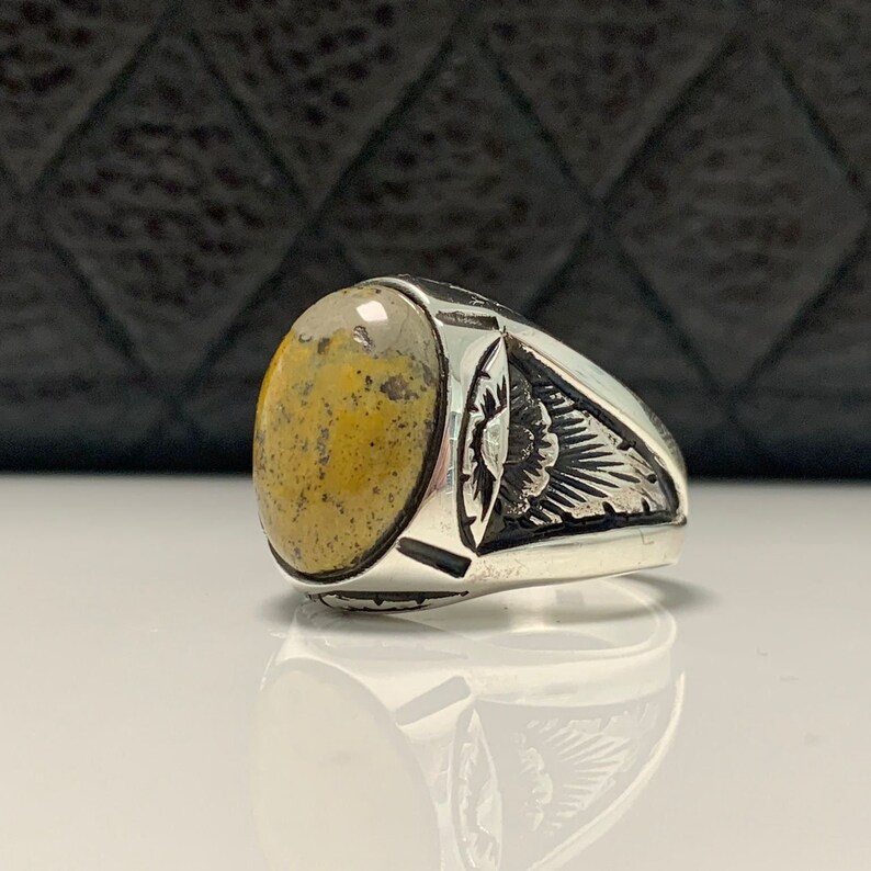 Peut inclure: Une bague en argent avec une pierre ovale jaune et brune. La bague a un design d&eacute;taill&eacute; sur la bande.