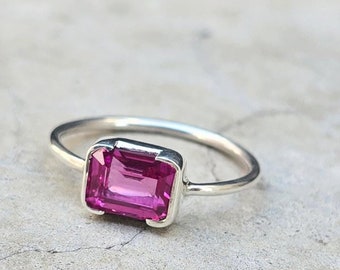 May include: A silver ring with a pink rectangular gemstone.