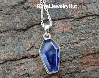 May include: A silver chain necklace with a pendant featuring a dark blue gemstone in a coffin shape.
