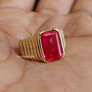 Op de afbeelding: Een gouden ring met een grote, helderrode, smaragd geslepen edelsteen.