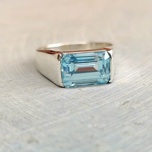Può includere: Un anello d'argento con una pietra rettangolare di colore blu chiaro.