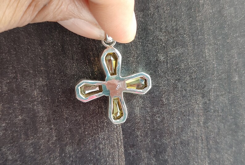 May include: Silver cross pendant with four clear yellow faceted stones.