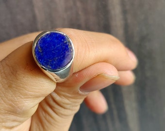 Op de afbeelding: Een zilveren ring met een grote, ronde, blauwe lapis lazuli-edelsteen.