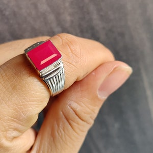 Può includere: Un anello d'argento con una pietra preziosa quadrata di colore rosso brillante.