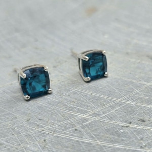 May include: A pair of silver stud earrings with square blue gemstones.