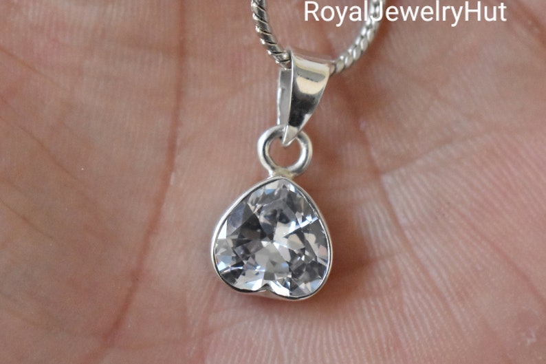 Puede incluir: Un colgante de plata con un cristal transparente en forma de coraz&oacute;n. El colgante est&aacute; en una cadena de plata.