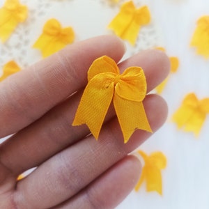 Peut inclure: Un gros plan sur un nœud en tissu jaune. Le nœud est tenu dans une main, et il y a d'autres nœuds en arrière-plan.