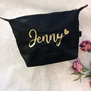 May include: Black zippered makeup bag with a gold inscription that reads "Jenny" with a small gold heart.