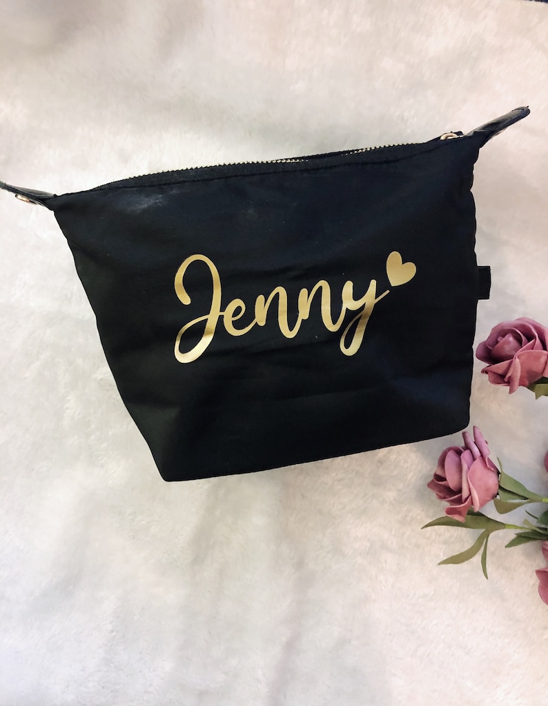 May include: Black zippered makeup bag with a gold inscription that reads "Jenny" with a small gold heart.