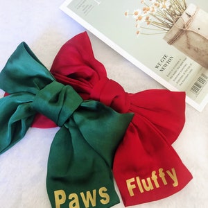 May include: Two large satin bows, one green and one red, with gold lettering. The green bow says "Paws" and the red bow says "Fluffy".