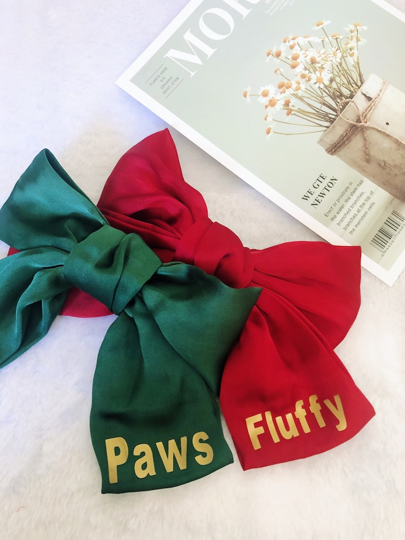 May include: Two large satin bows, one green and one red, with gold lettering. The green bow says "Paws" and the red bow says "Fluffy".