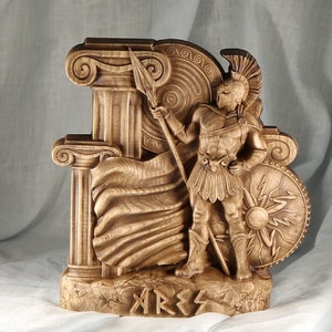 A wooden sculpture of the Greek god Ares, depicted as a warrior holding a spear and shield next to Greek columns, pagan altar decor.