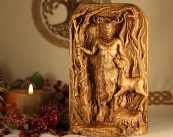 May include: A wooden carving of a horned deity standing in a forest setting. The deity is holding a staff and has a deer at their side. The carving is detailed and intricate, with a rustic finish.