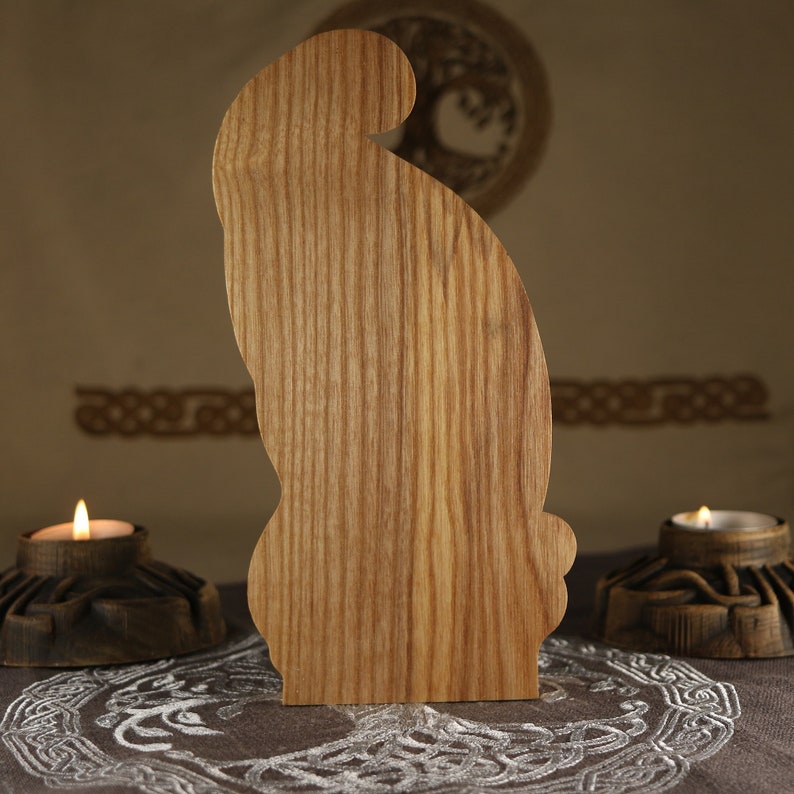 Op de afbeelding: Een houten uitsnijding van een konijn, staand op een donker oppervlak met een wit ontwerp. Het konijn is gemaakt van lichtbruin hout met zichtbare nerven.