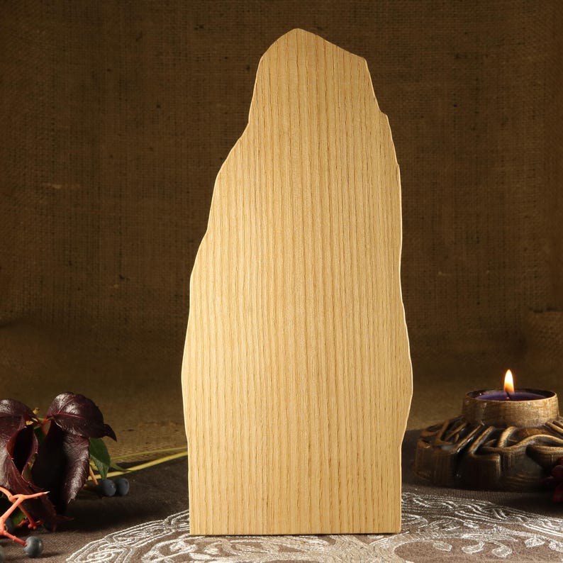 May include: A wooden cutout of a tall, thin rock formation with a rough, irregular shape. The cutout is made of light-colored wood with visible grain.